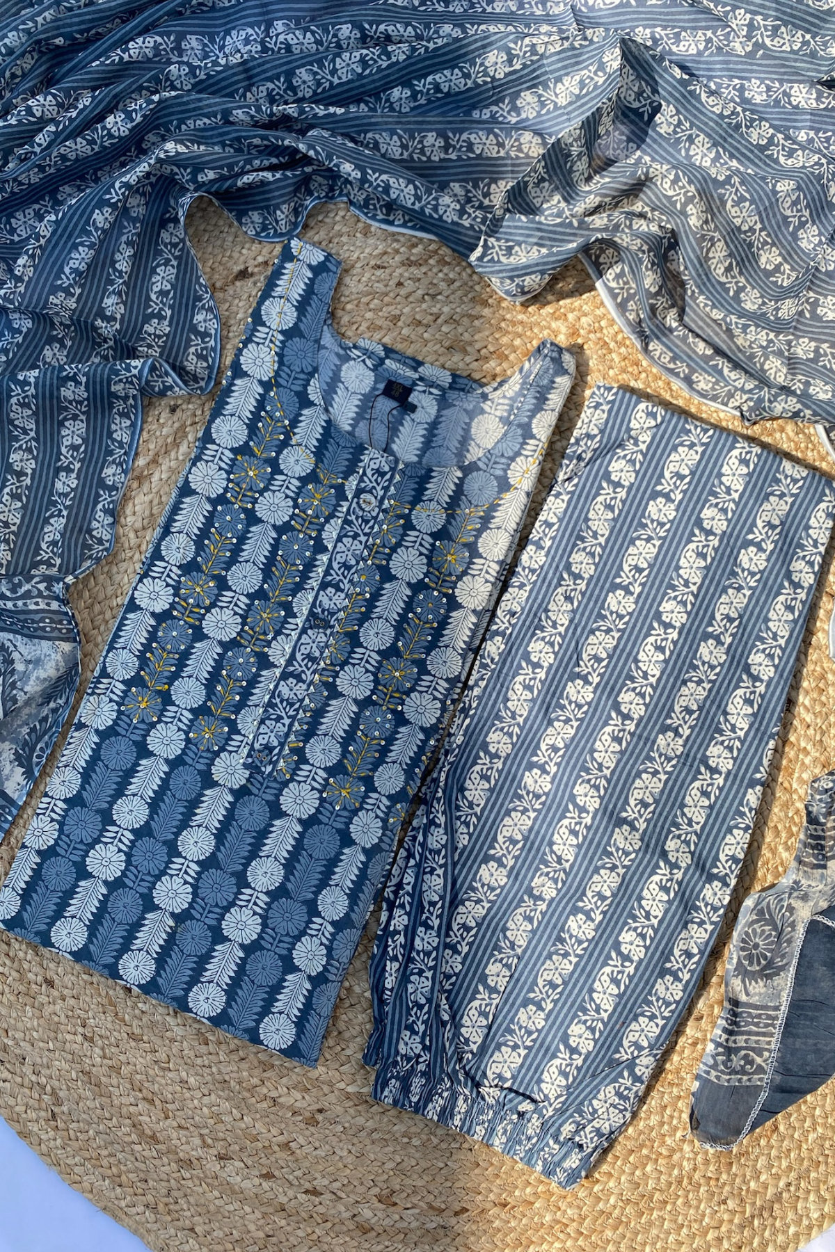 A plus size cotton suit set with dupatta, featuring a blue and white geometric pattern, displayed on a straw mat.