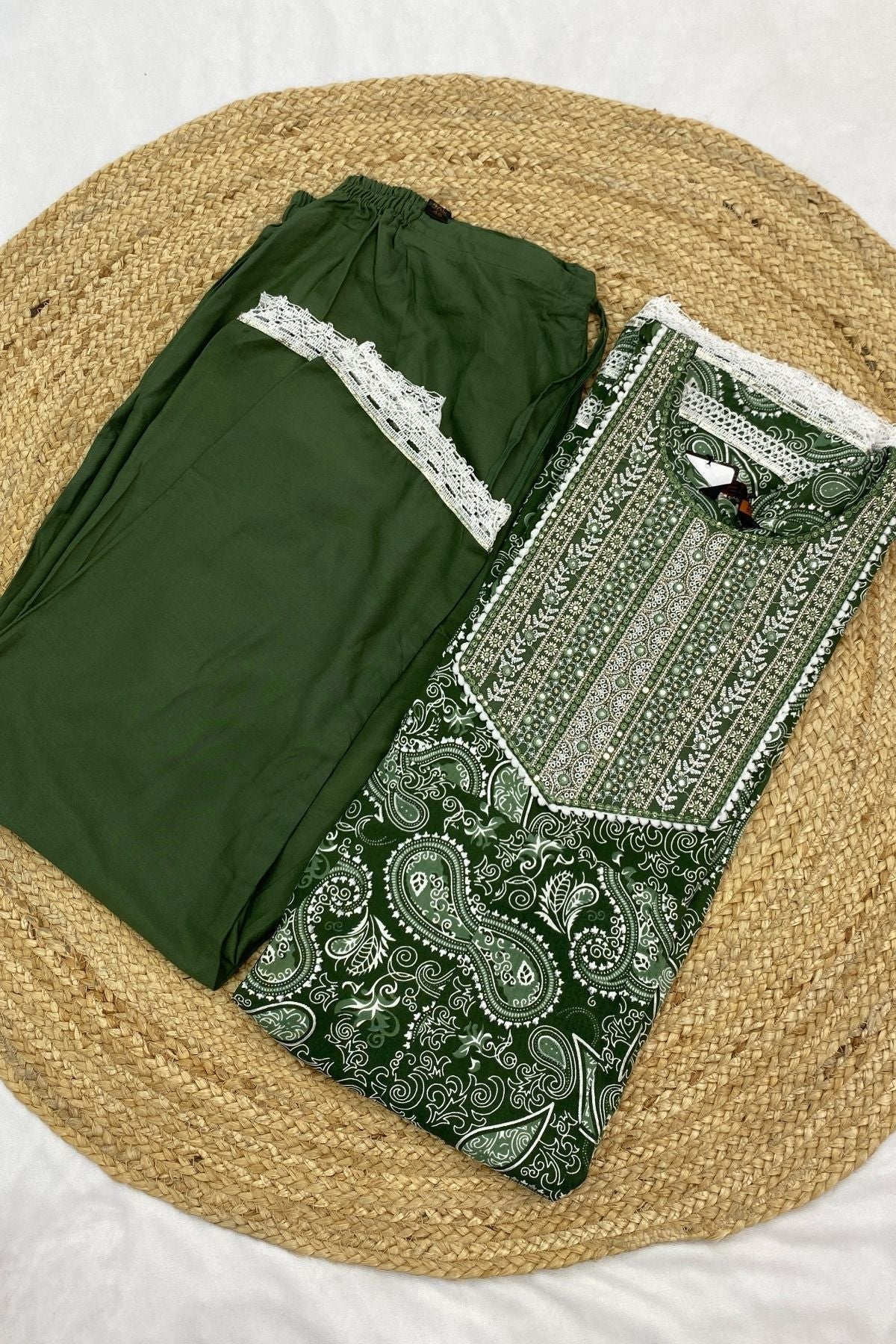Green traditional outfit with paisley patterns on a woven mat